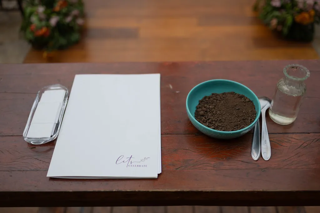 O livro de assinaturas aberto sobre a mesa de madeira, ao lado das alianças.