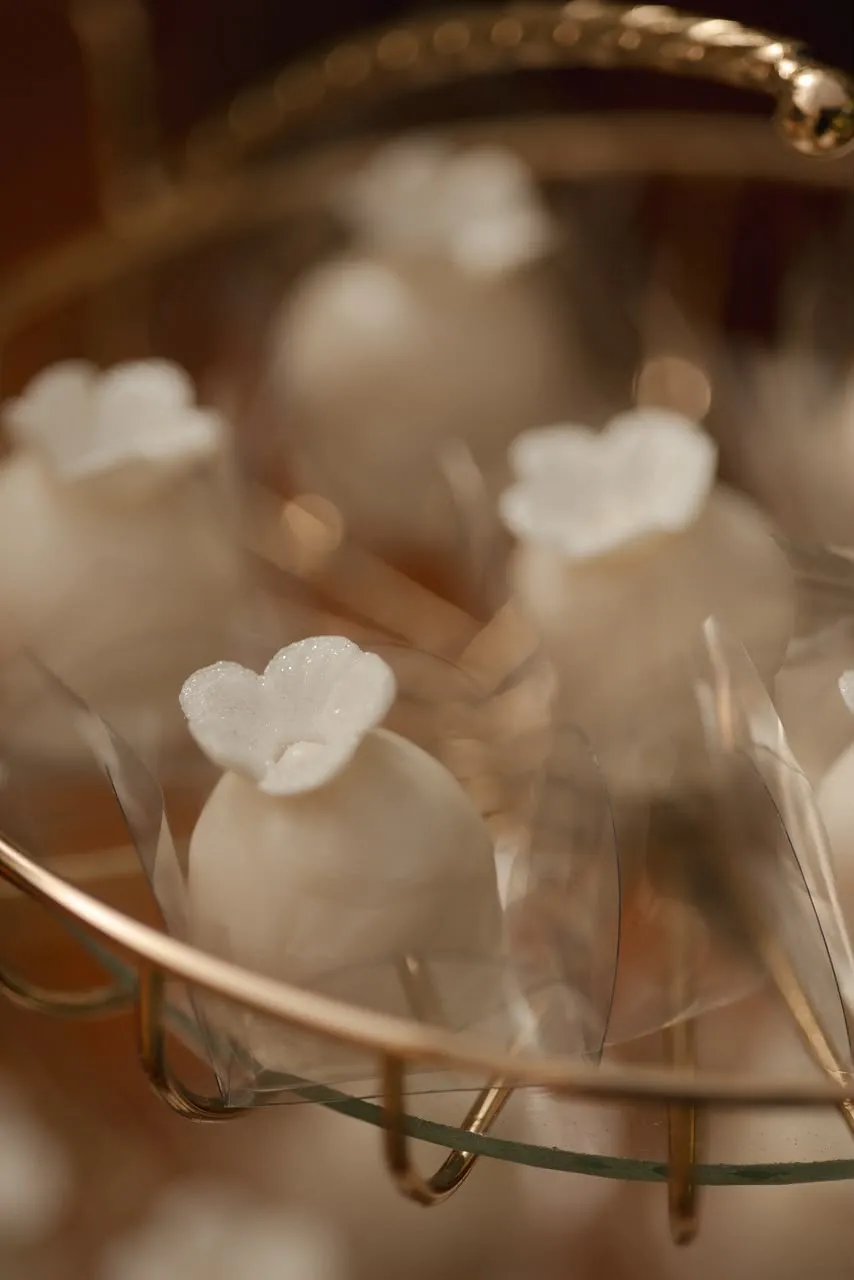 Doces em forma de flor dispostos numa bandeja dourada.