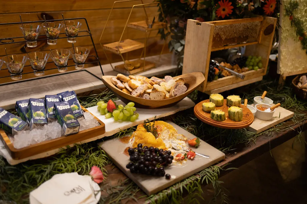 Tábuas de queijos e frutas dispostas na mesa de madeira.